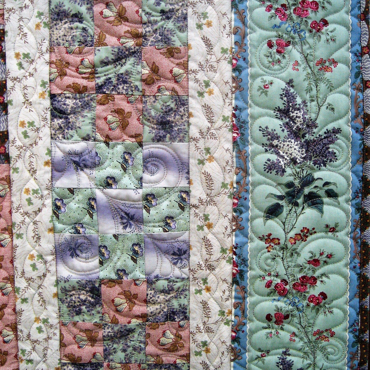 A close-up of a handmade quilted textile featuring multiple vertical panels with different floral and paisley patterns in pastel shades of mint green, dusty pink, lavender, and cream.