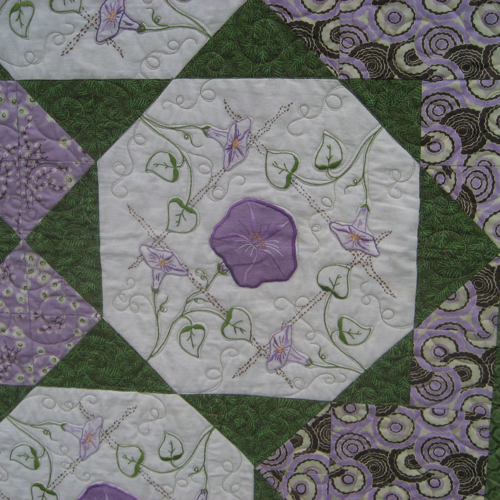 Close up of a quilt block with a floral applique in purple and green