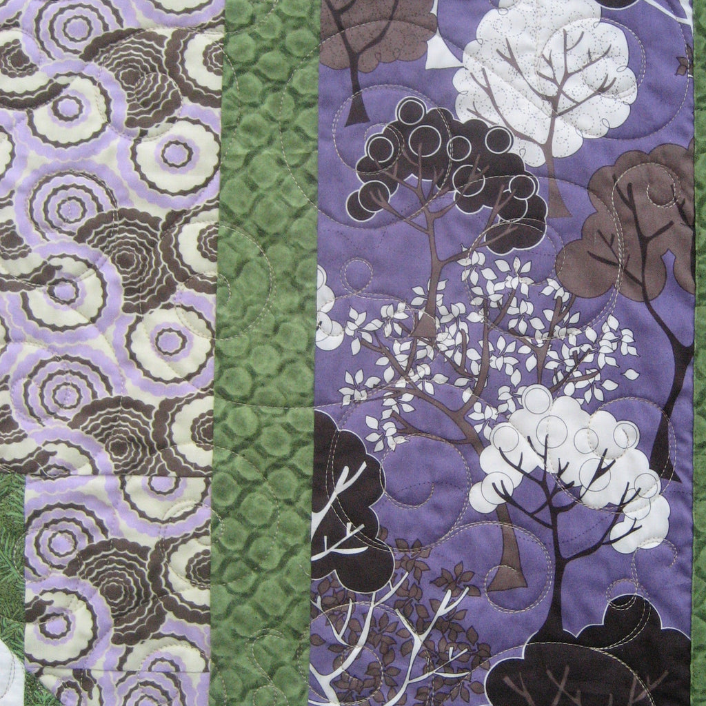 Quilt block with a floral and woodsy pattern in green and purple