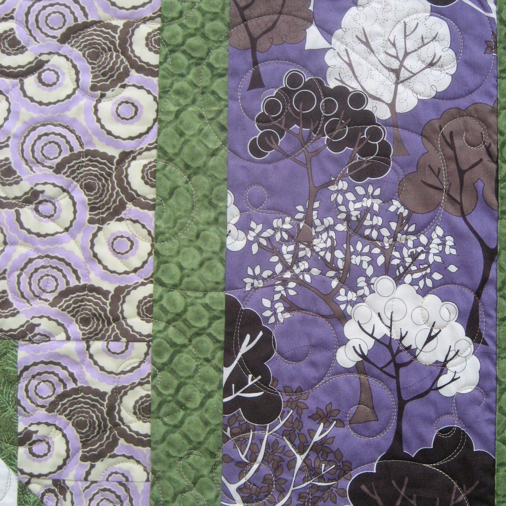 Quilt block with a floral and woodsy pattern in green and purple