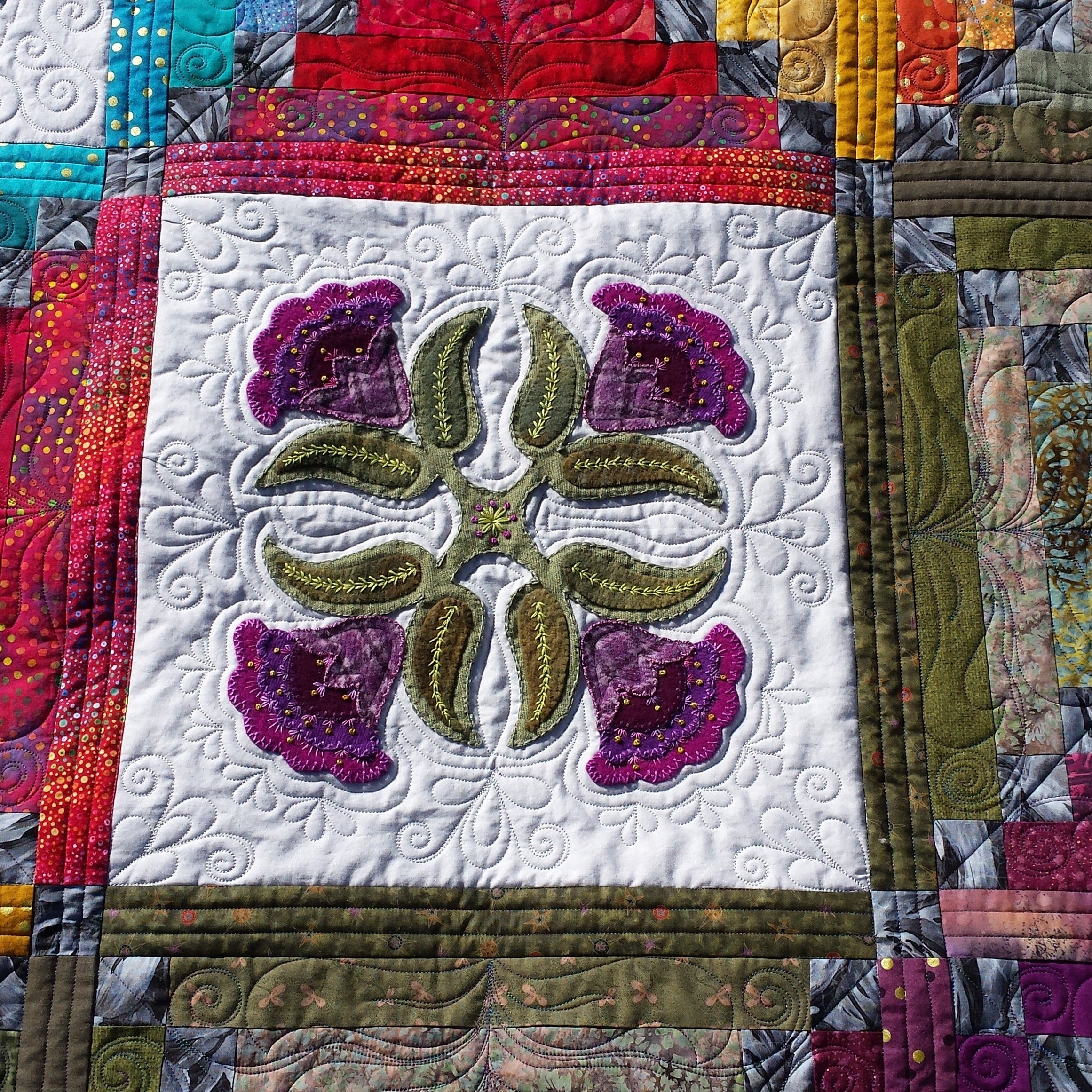 Colorful quilt with floral design and multicolored border