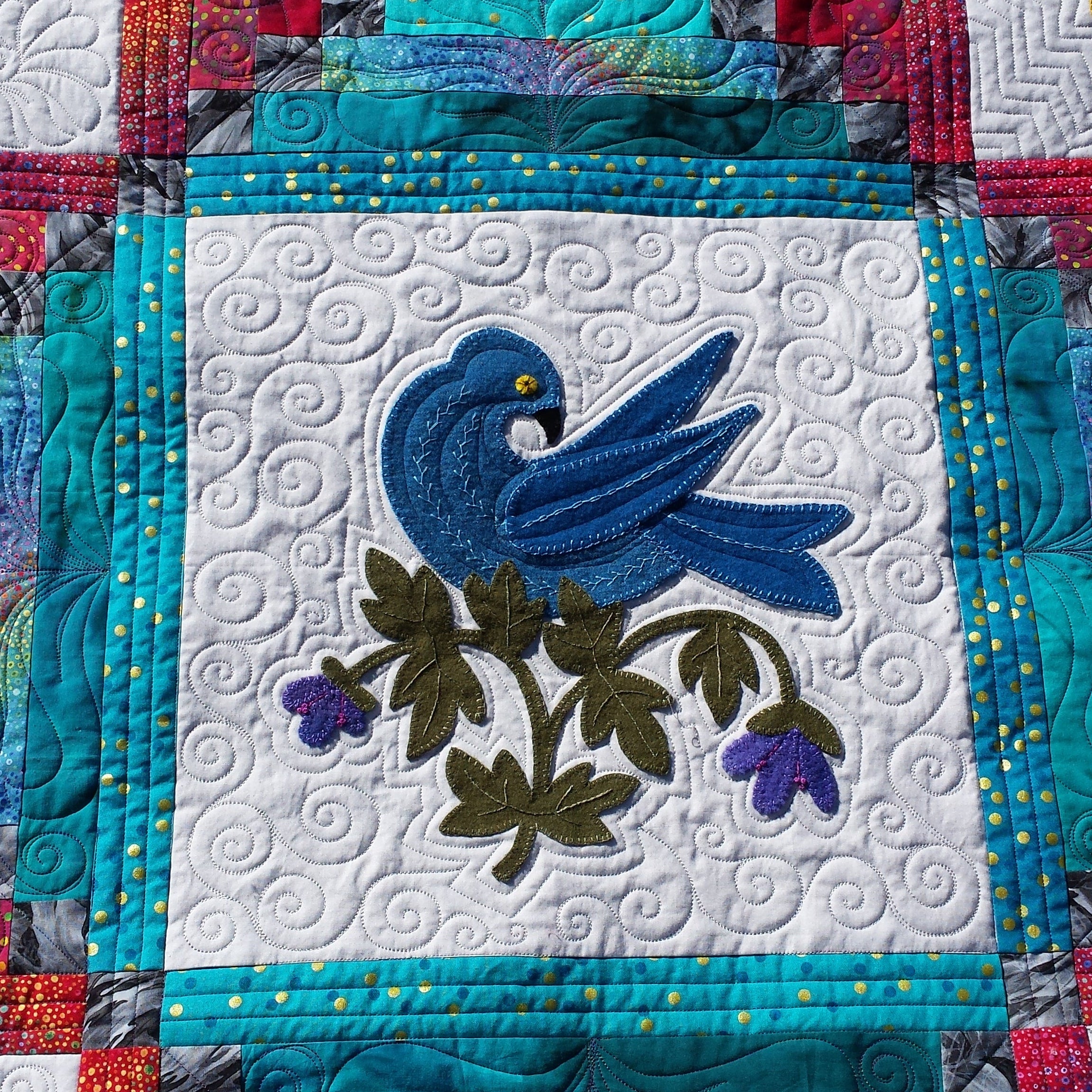 Quilt block with a blue bird design on a colorful background