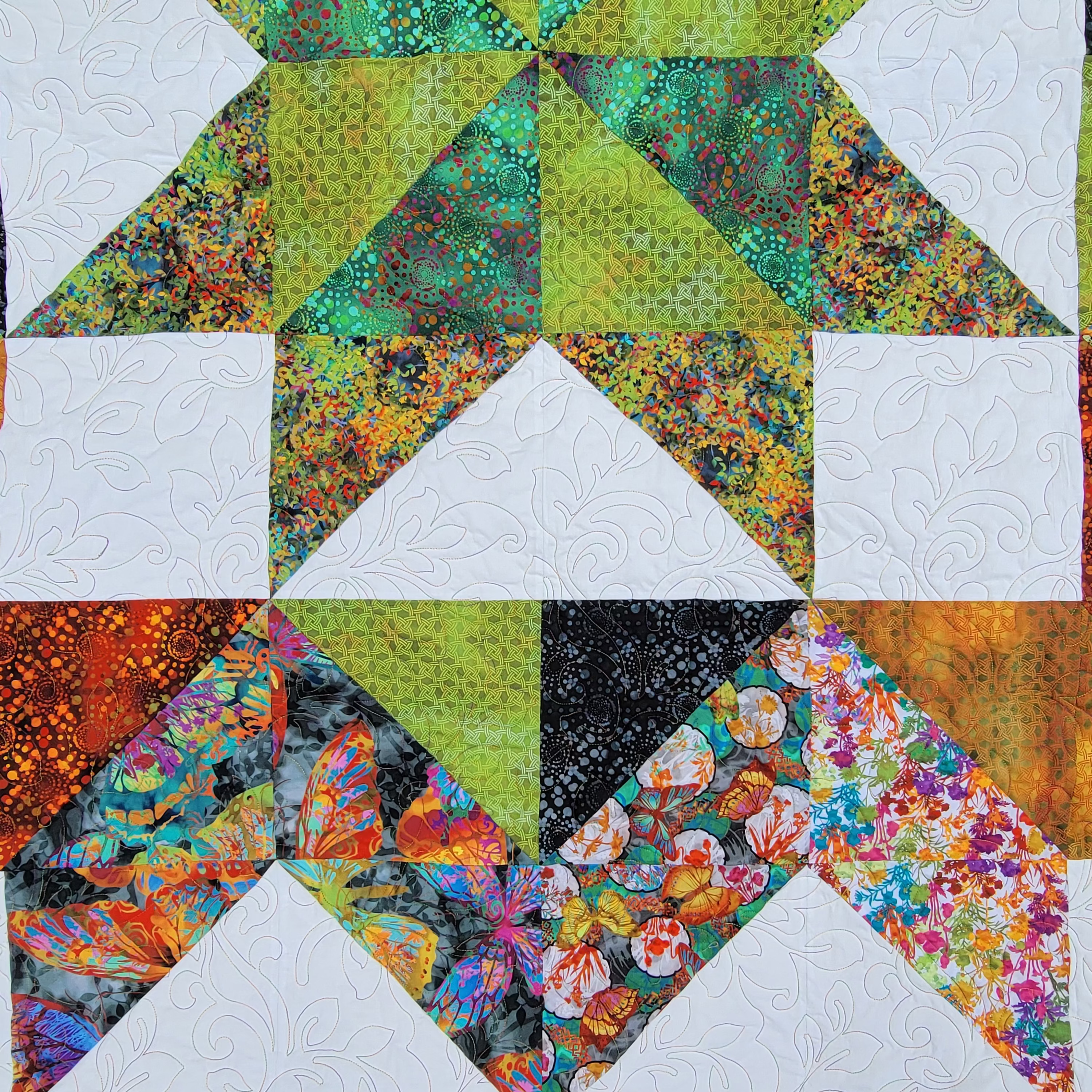 Colorful quilt with geometric pattern featuring triangles and squares.