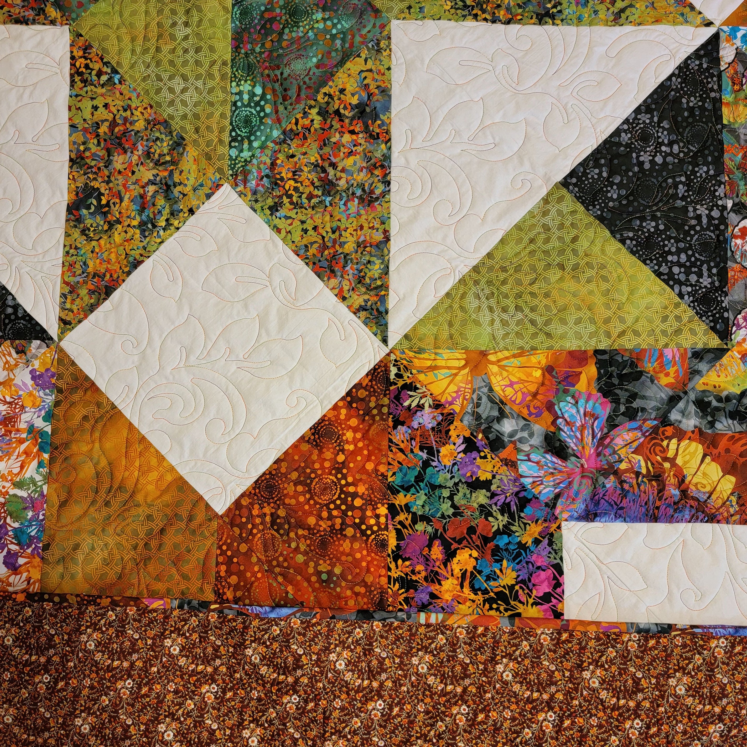 Colorful quilt with geometric patterns and floral designs.