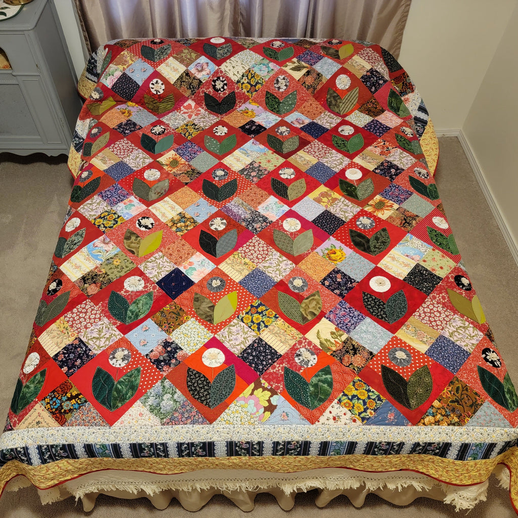 Colorful quilt on a bed in a room with a gray dresser.