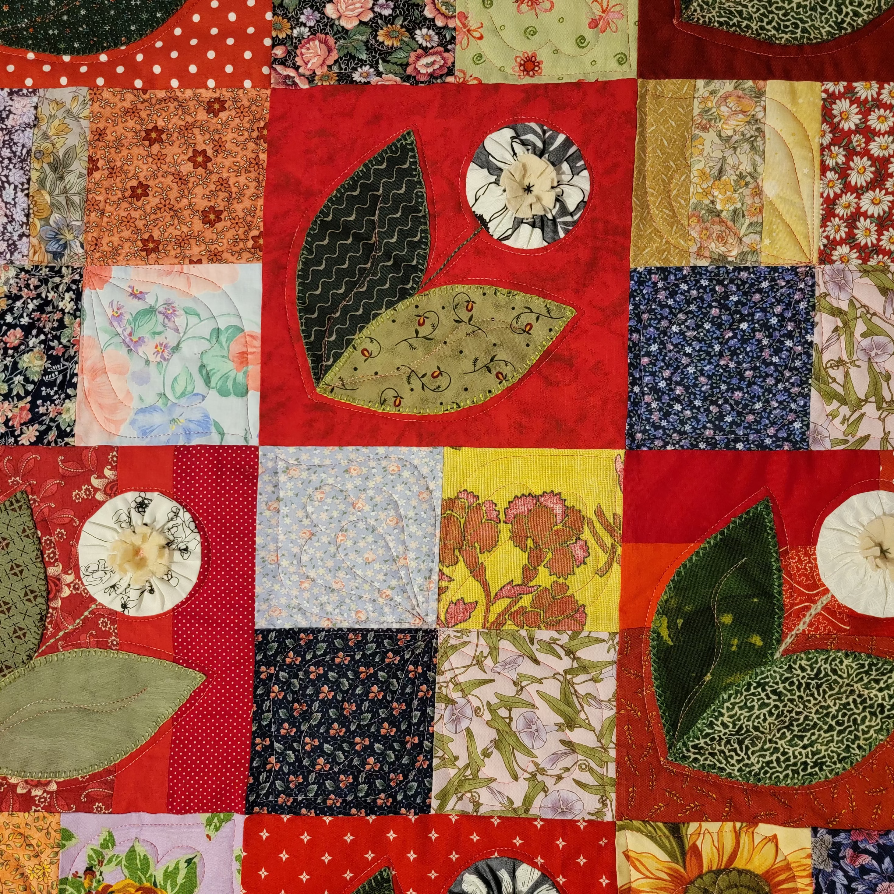 Quilt with floral and leaf patterns on a red background