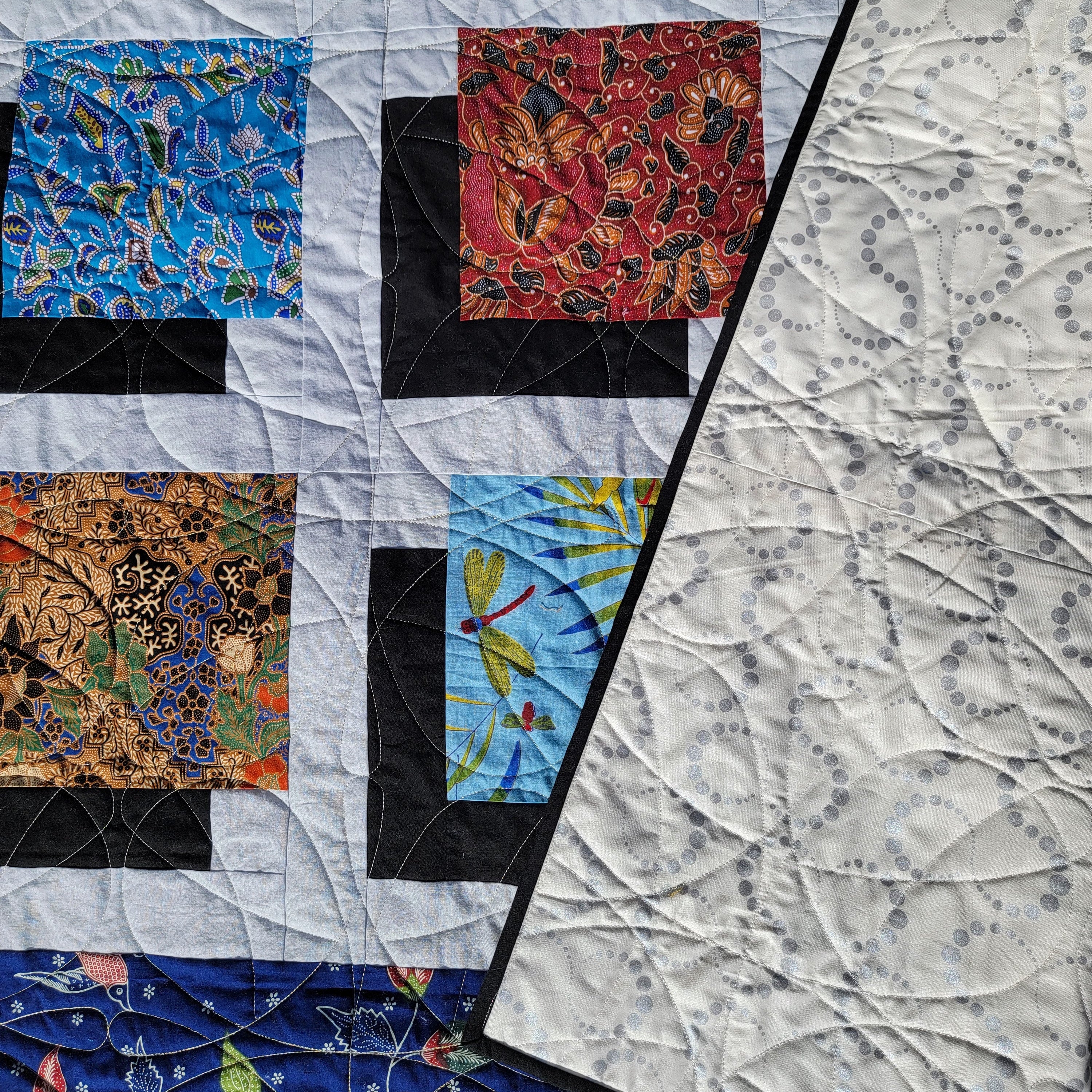 Quilt with various patterned squares on a textured fabric background