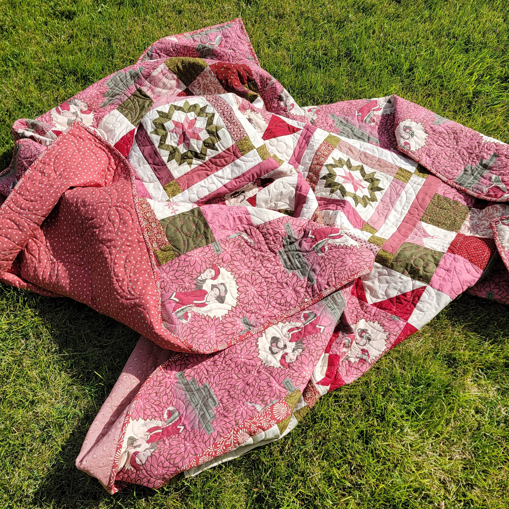 Pink patterned quilt laid out on grass