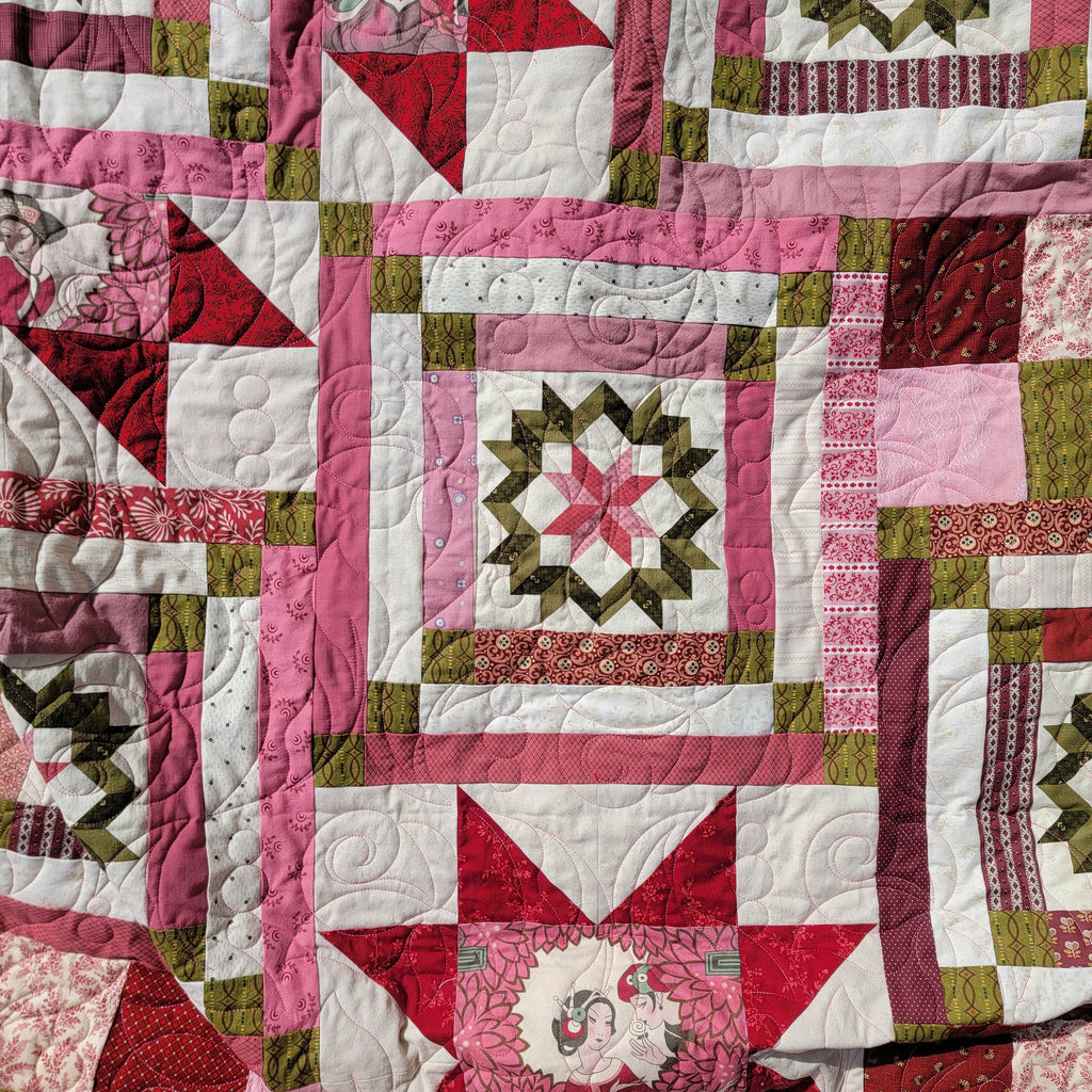 Quilt block in a star print in green and pink with patterned surrounding