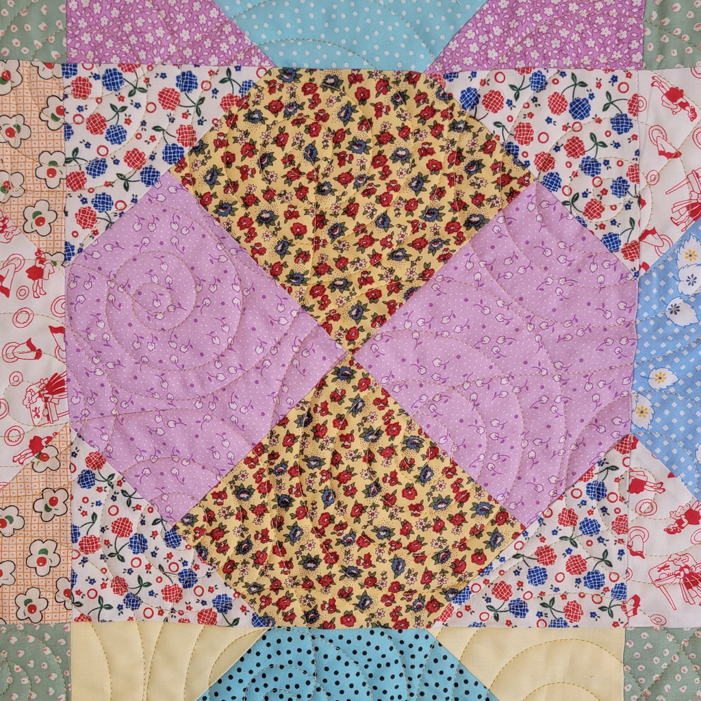 A close up of a quilt in pastel purple and blue tones with multiple prints and patterns. 