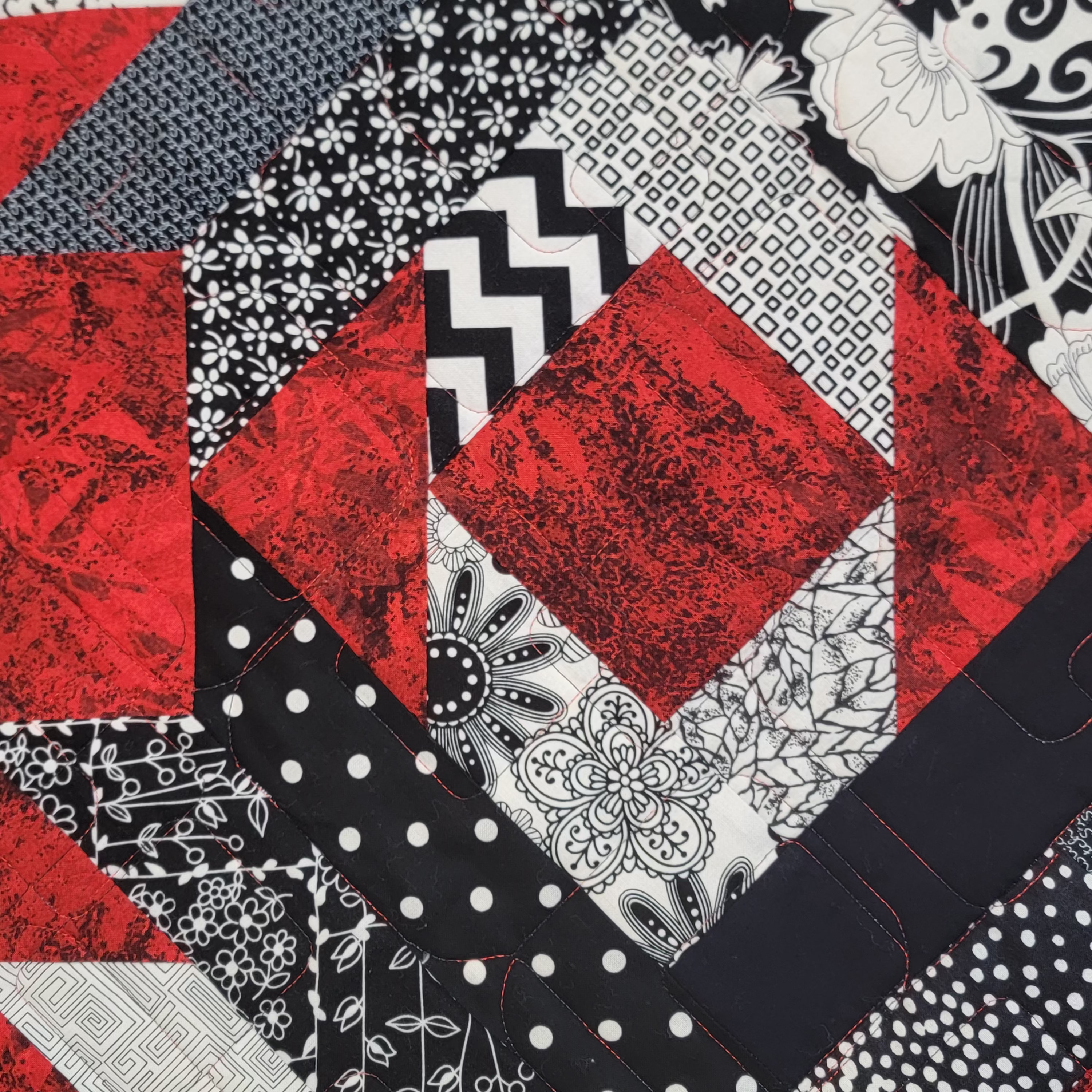 A close up of a geometric print made up of red, white and black prints. 