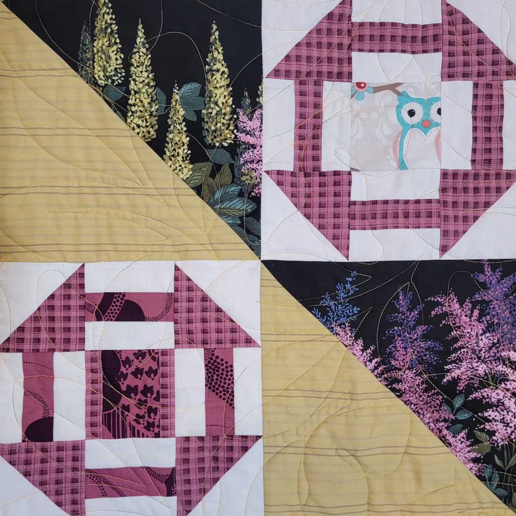 Close up of a quilt with multiple floral and garden inspired prints in 4 different squares made up of triangles and geometric shapes. 