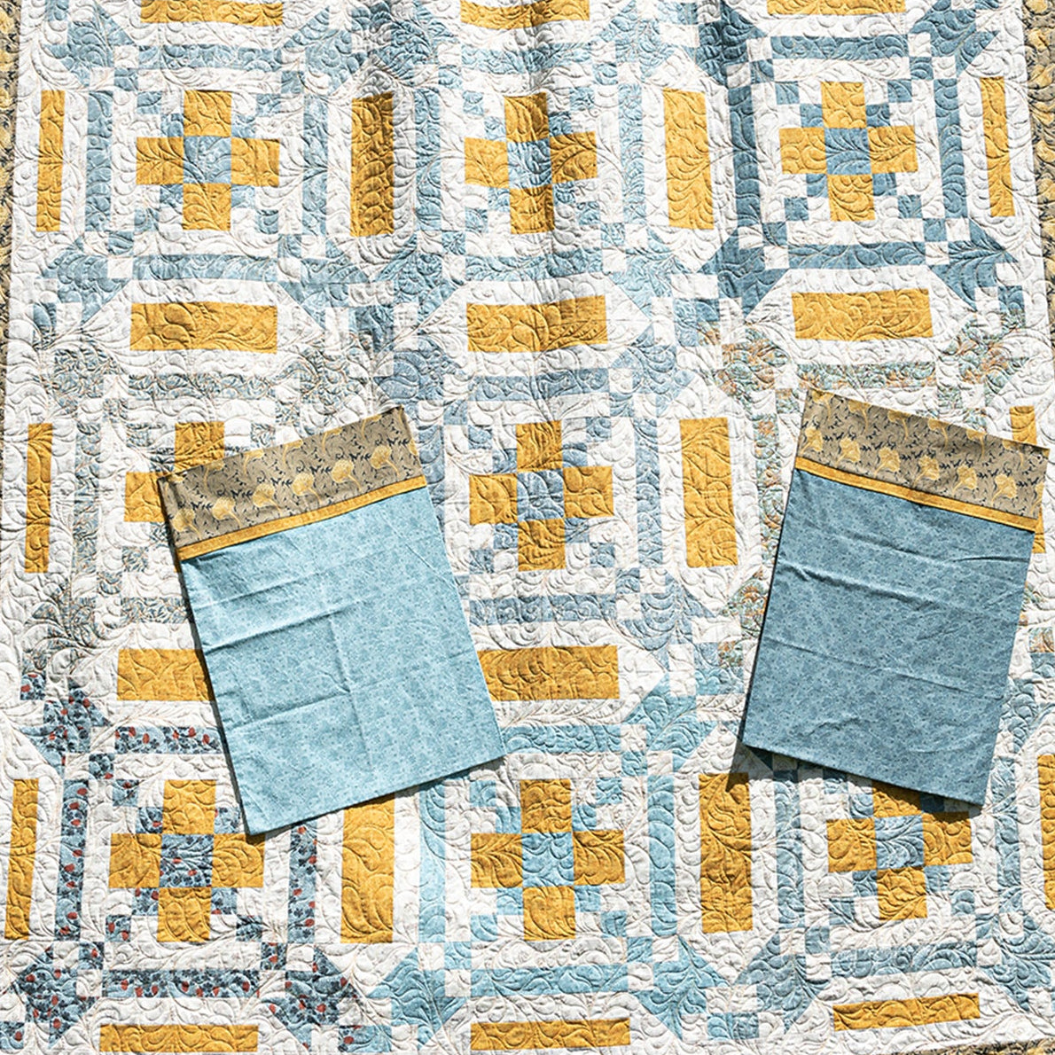 Quilt with geometric pattern and two blue pillowcases