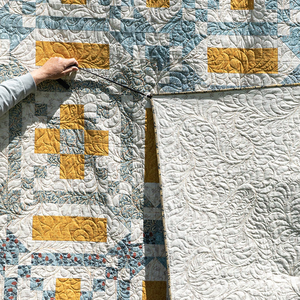 A quilt with one side patterned with geometric designs and the other solid white