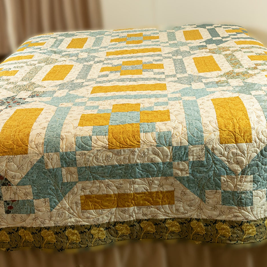 Quilt with geometric pattern on a bed in a room setting