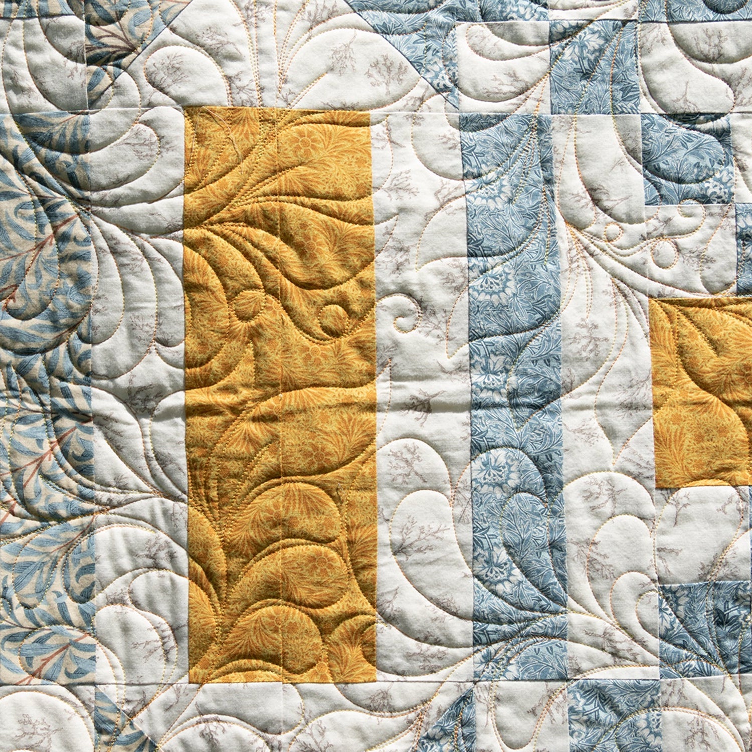 Quilt with a pattern of squares in blue, white, and yellow.