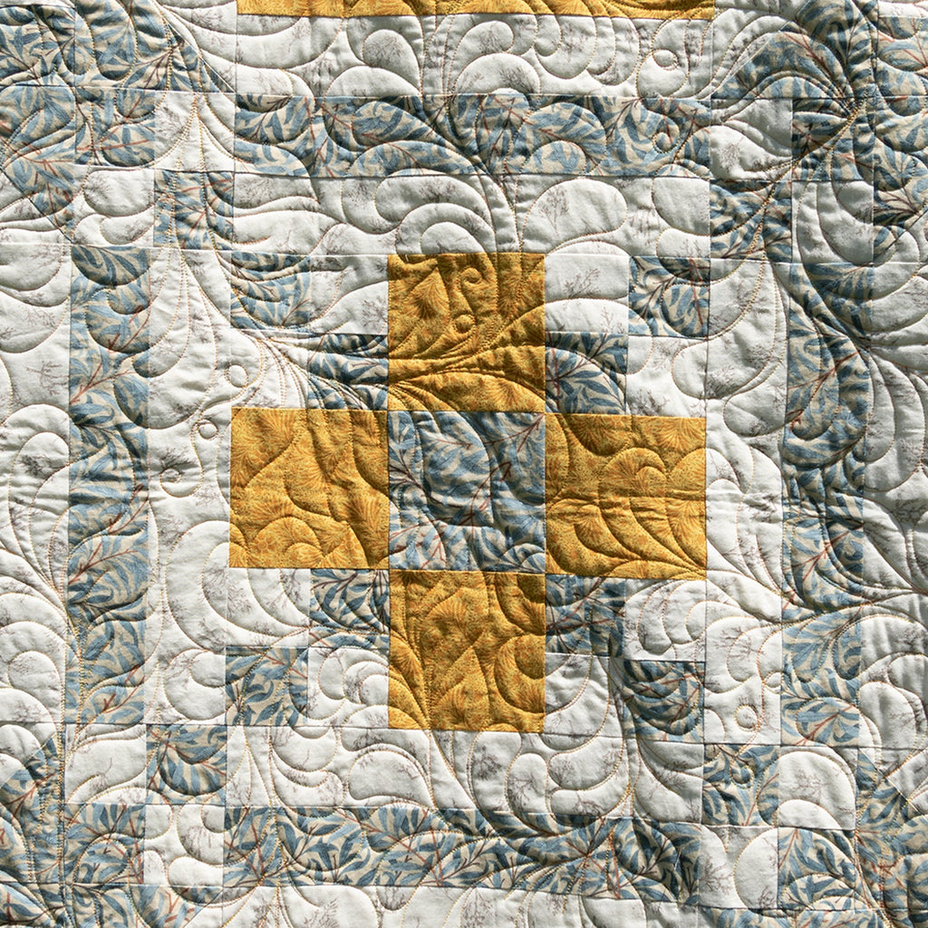Quilt with geometric pattern in gray and yellow on a textured fabric background