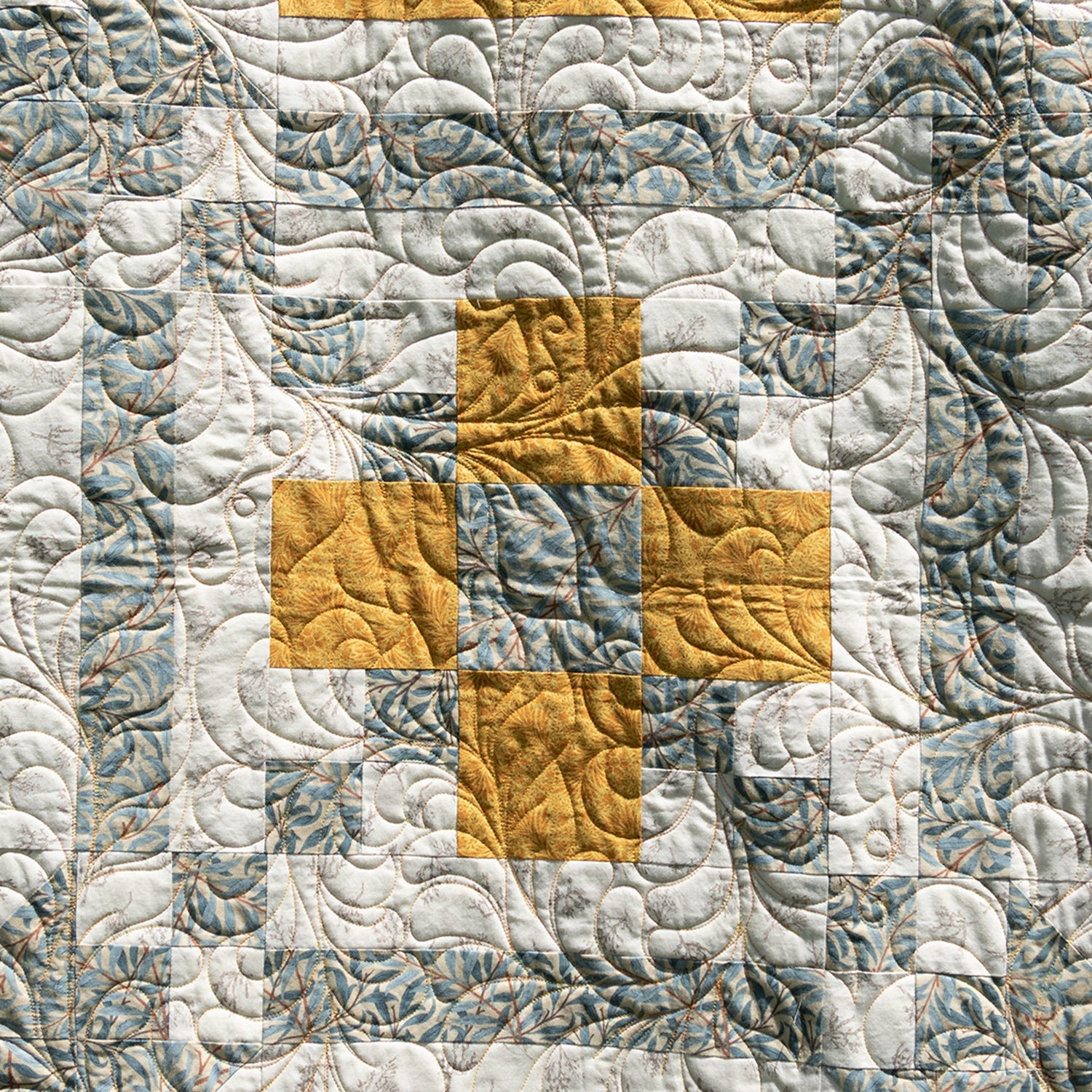 Quilt with geometric pattern in gray and yellow on a textured fabric background