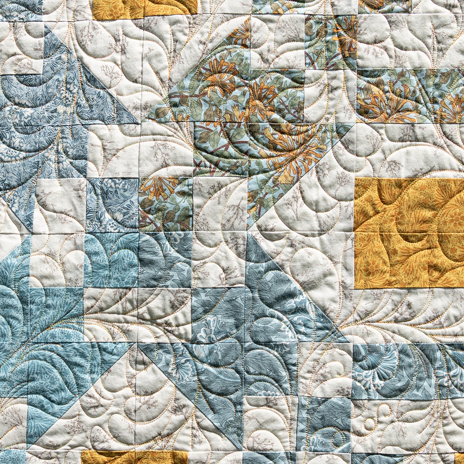 Quilt with a patchwork pattern featuring blue, white, and gold colors.