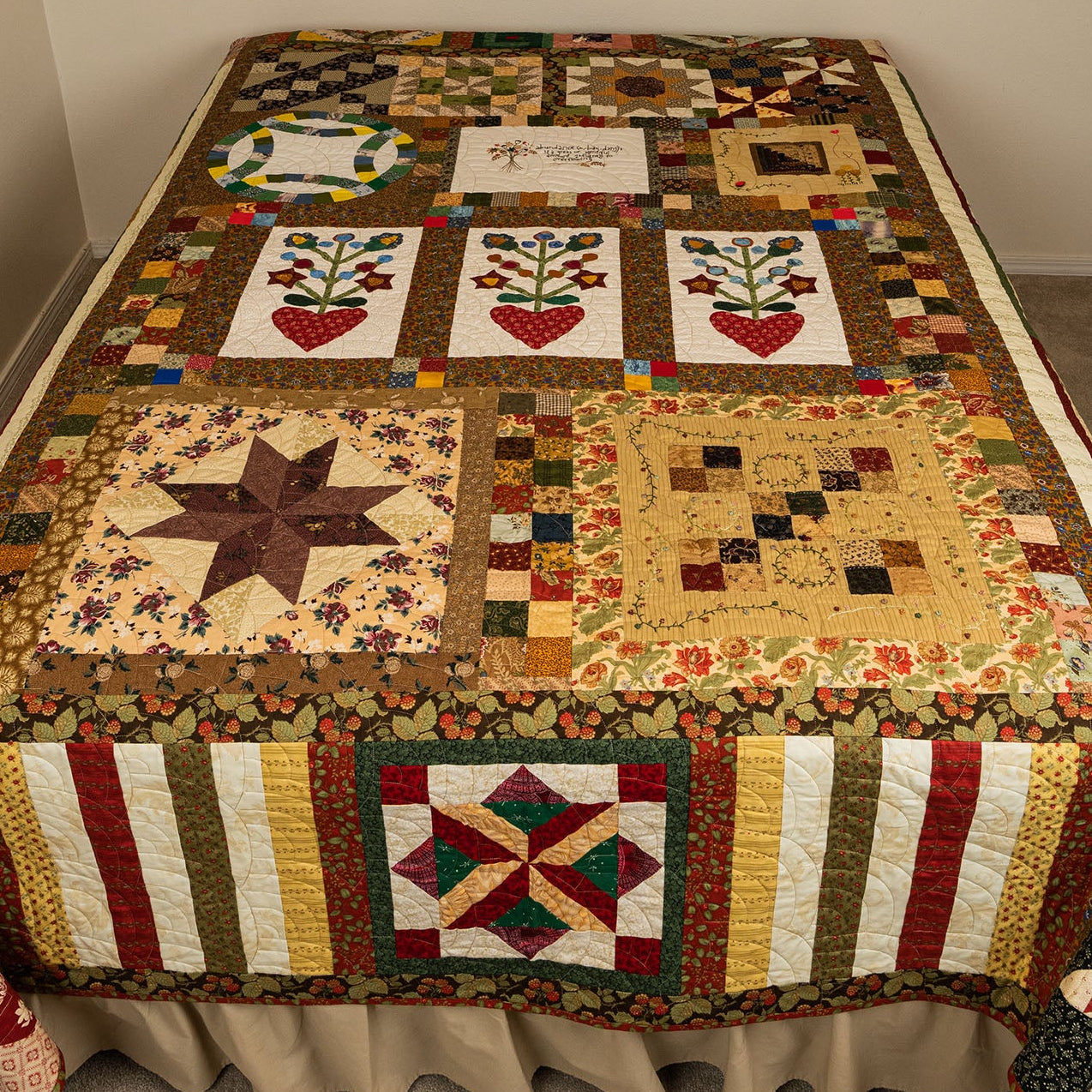 Quilt with various patterns on a bed in a room.