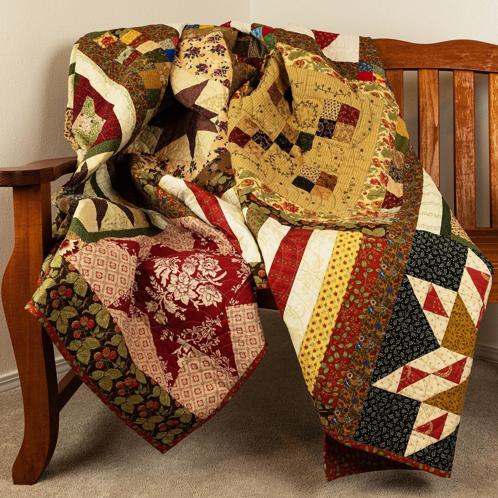 Colorful quilt draped over a wooden chair against a plain wall.