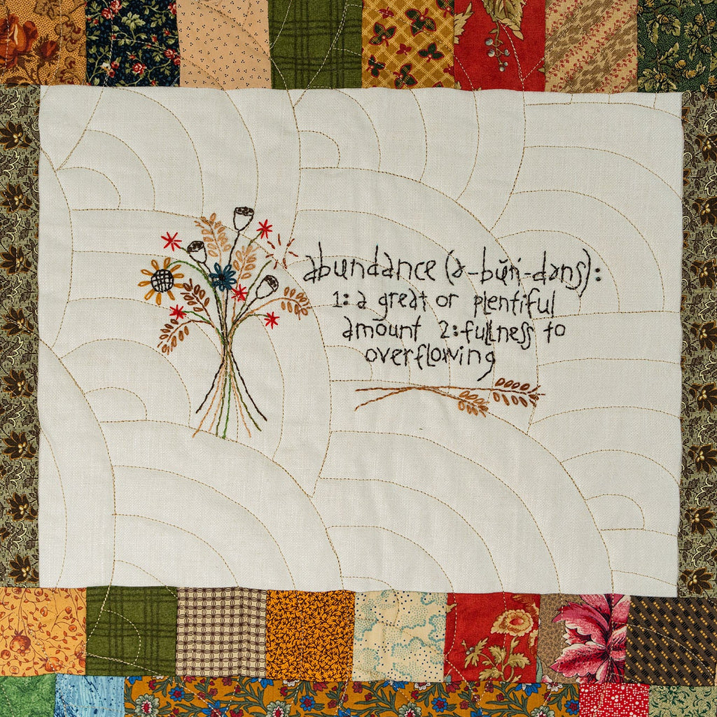Quilt with floral design and text on a patchwork border