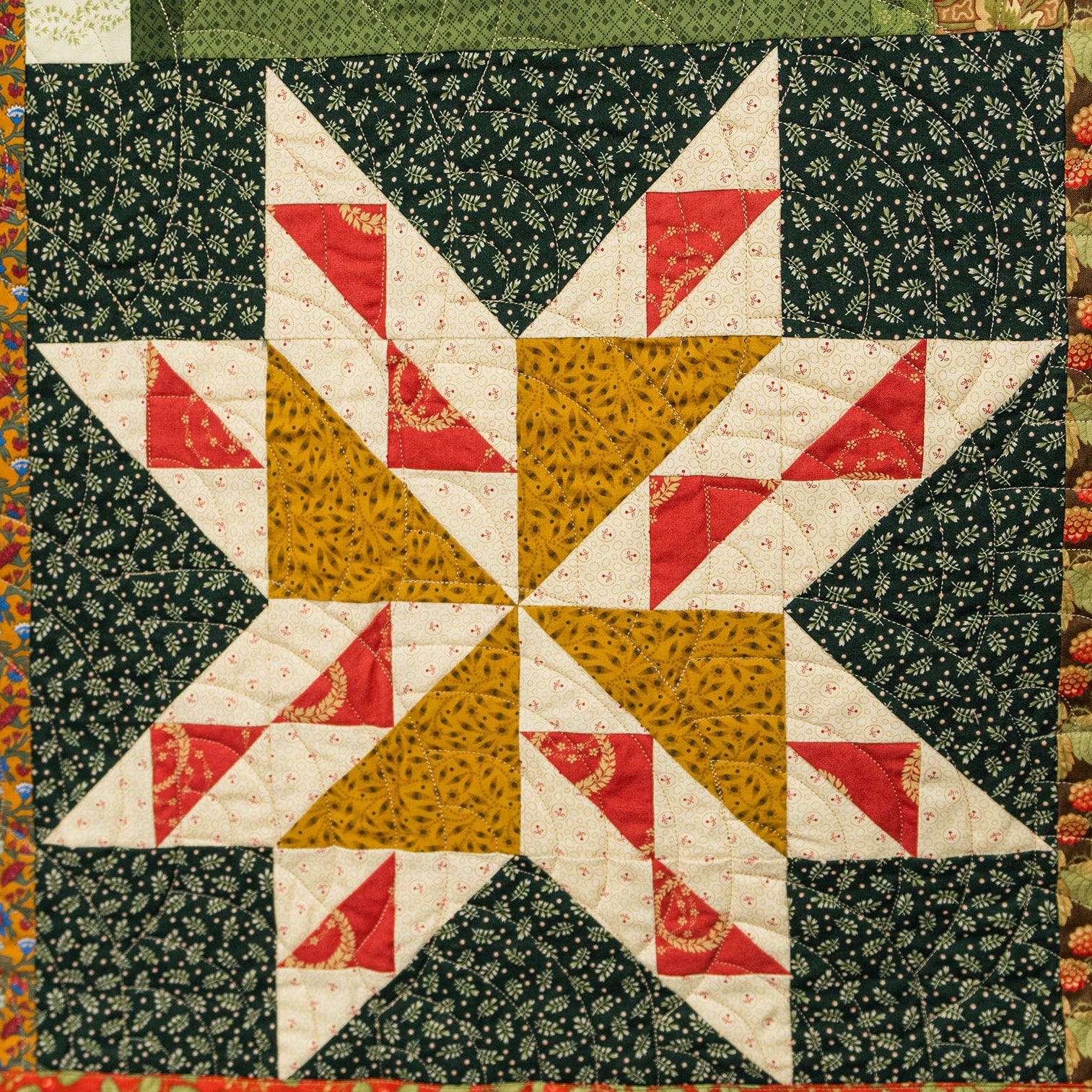 Quilt with star pattern featuring red, yellow, and white triangles on a green background.