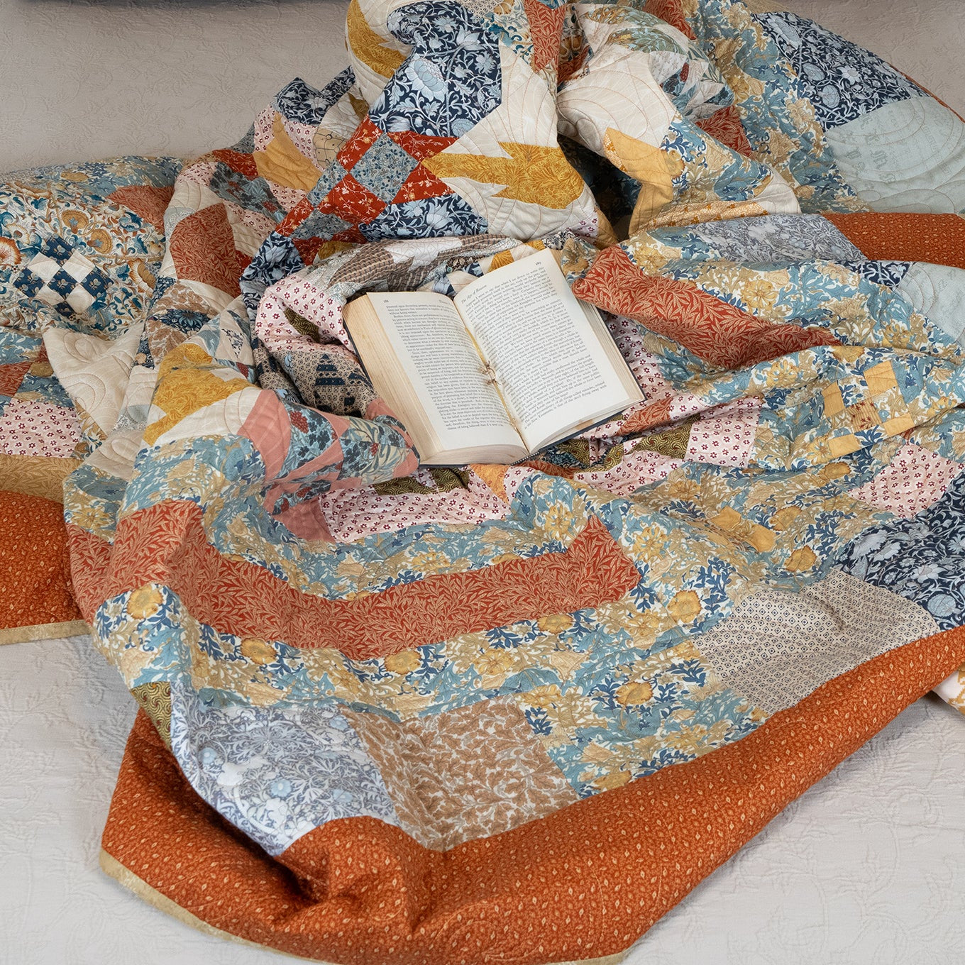 Colorful quilt with a book on top, lying on a white surface