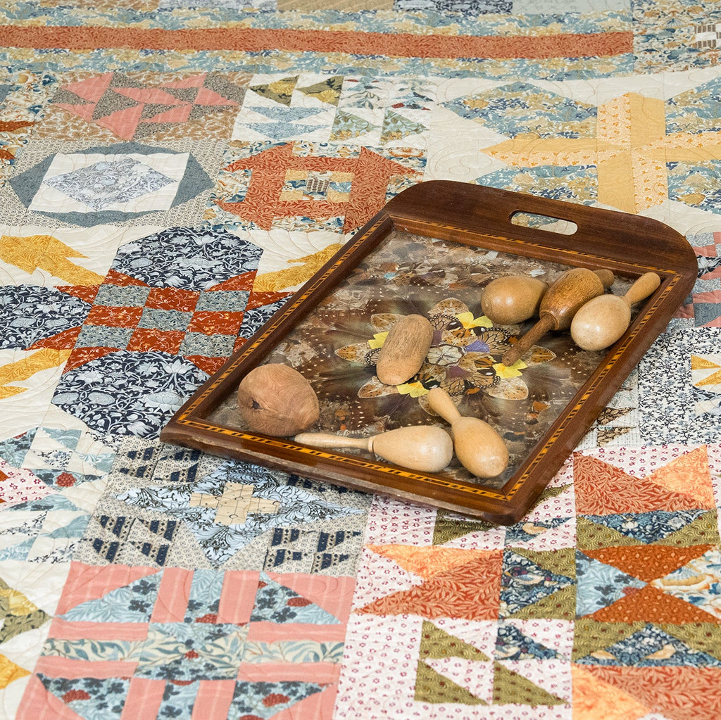 Wooden tray with rattles on a colorful quilt