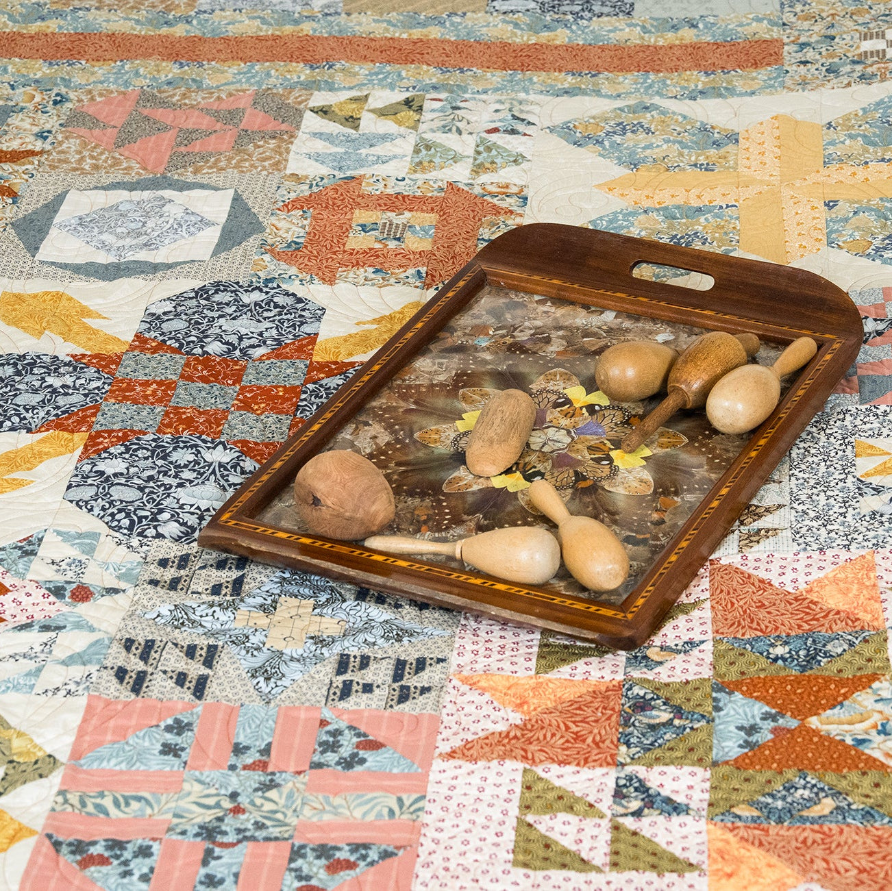 Wooden tray with rattles on a colorful quilt