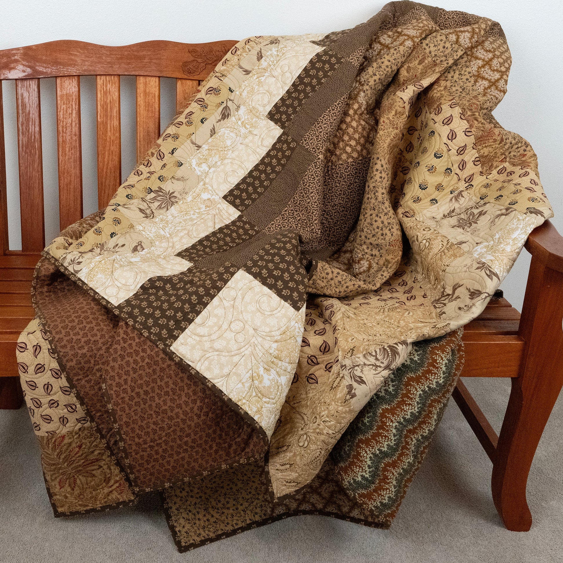 Patchwork quilt draped over a wooden chair with a neutral background