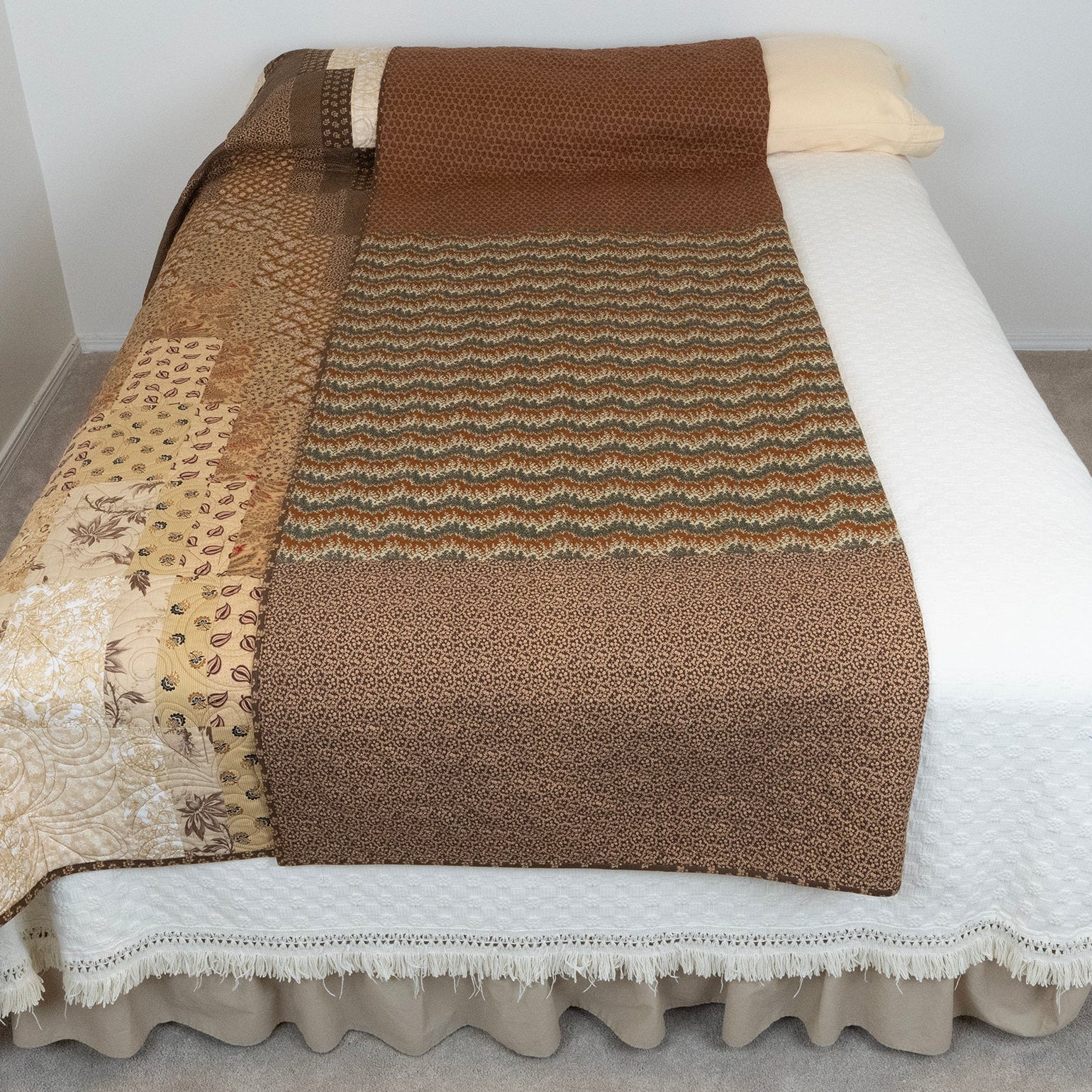 Brown textured blanket on a bed with a white pillow