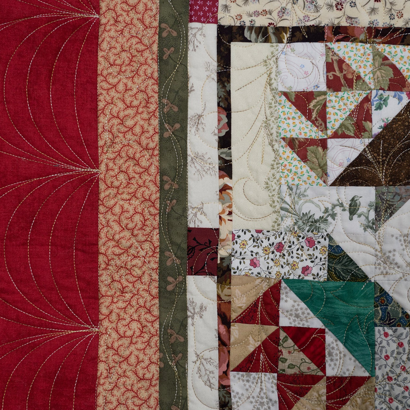 A close-up of a quilted fabric panel with a patchwork design. The left side features a large deep red section with curved quilting lines, bordered by narrow vertical stripes in beige, rust, and olive green.