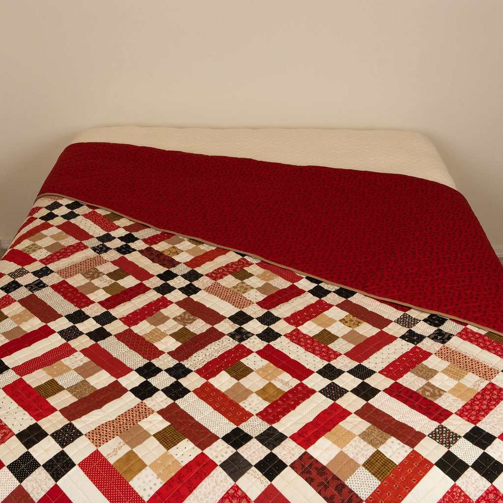 Quilt with a geometric pattern draped over a bed