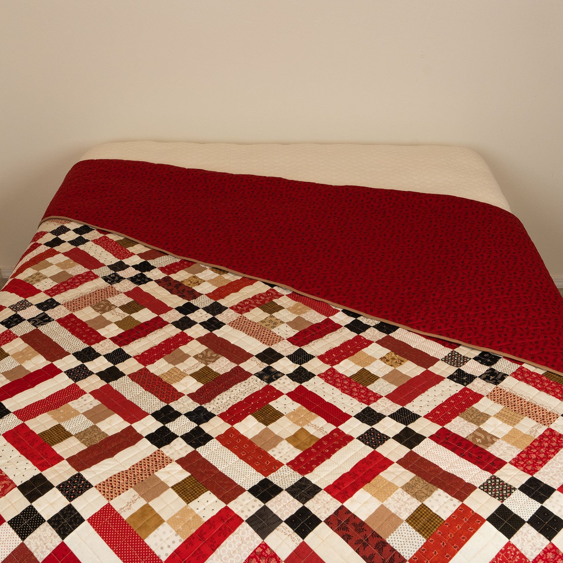Quilt with a geometric pattern draped over a bed