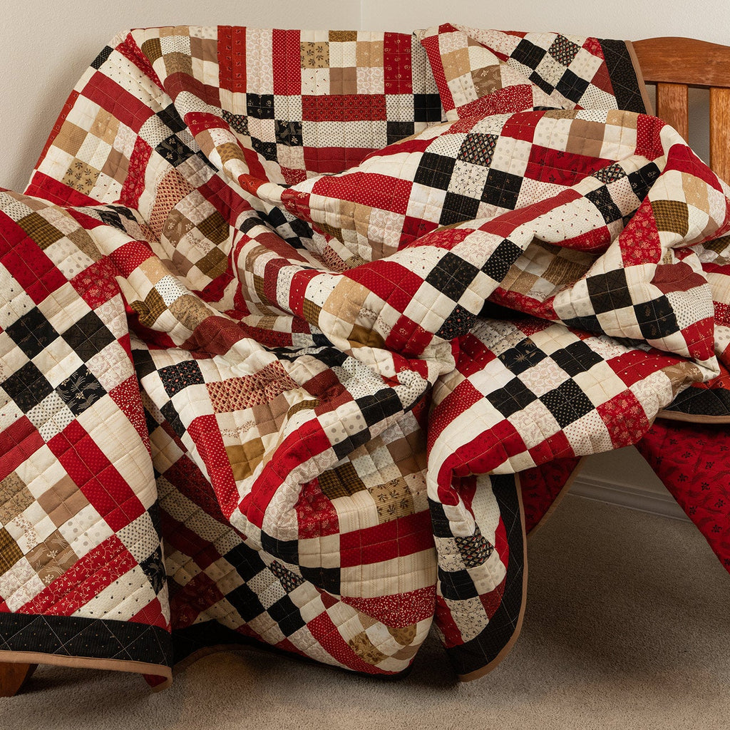 Quilt with a checkered pattern draped over a wooden chair.
