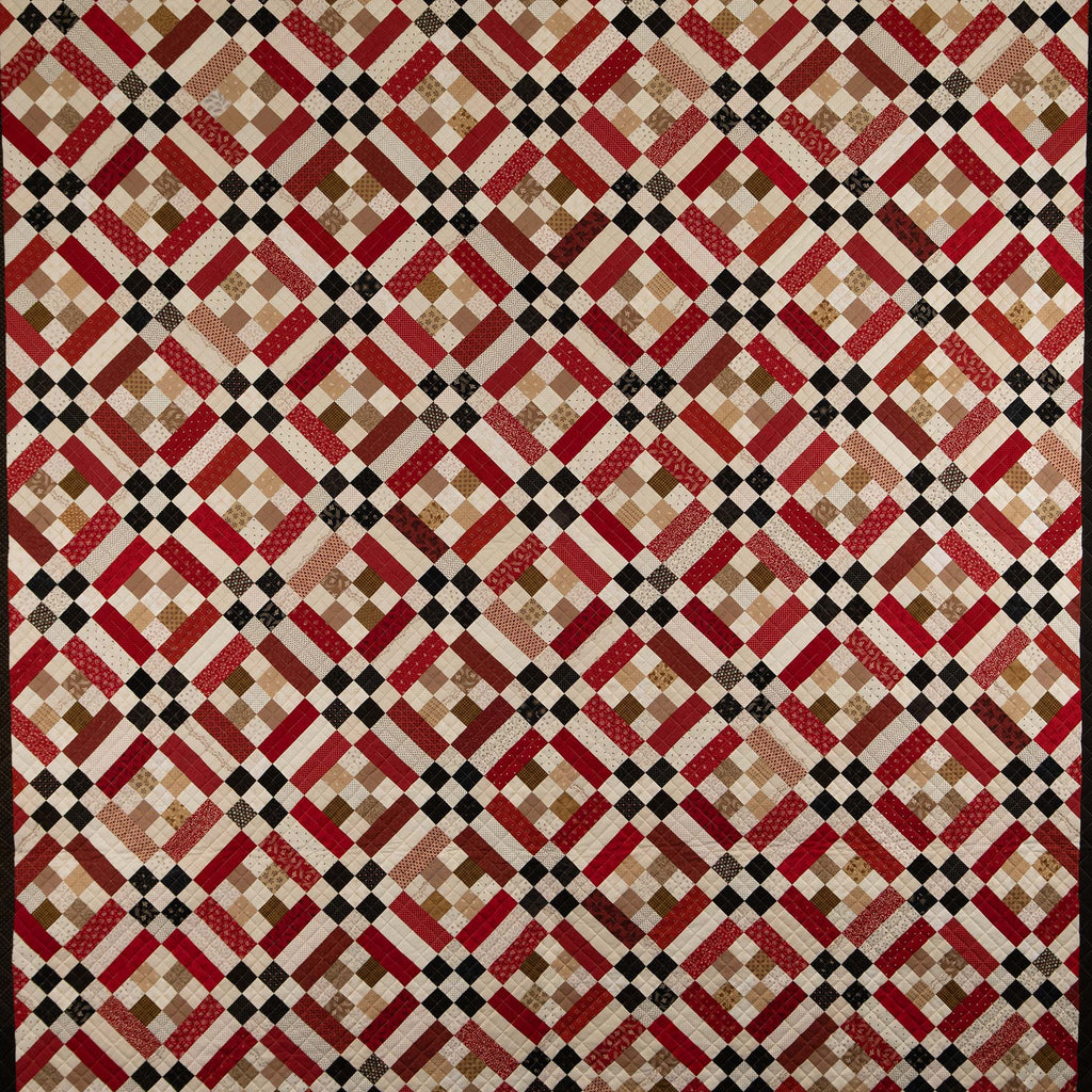 Quilt with a geometric diamond pattern in red, beige, and black
