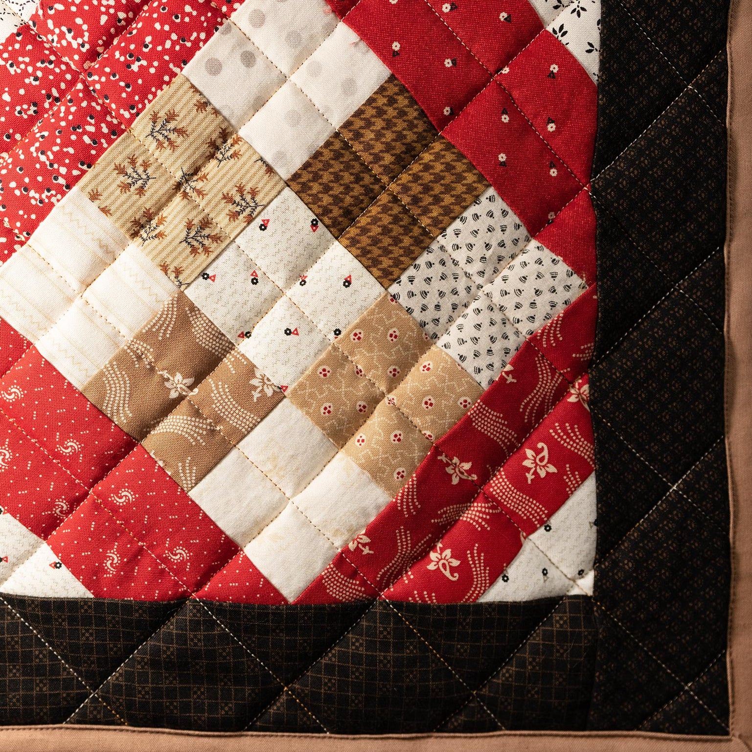 Quilt with red, white, and brown patchwork pattern