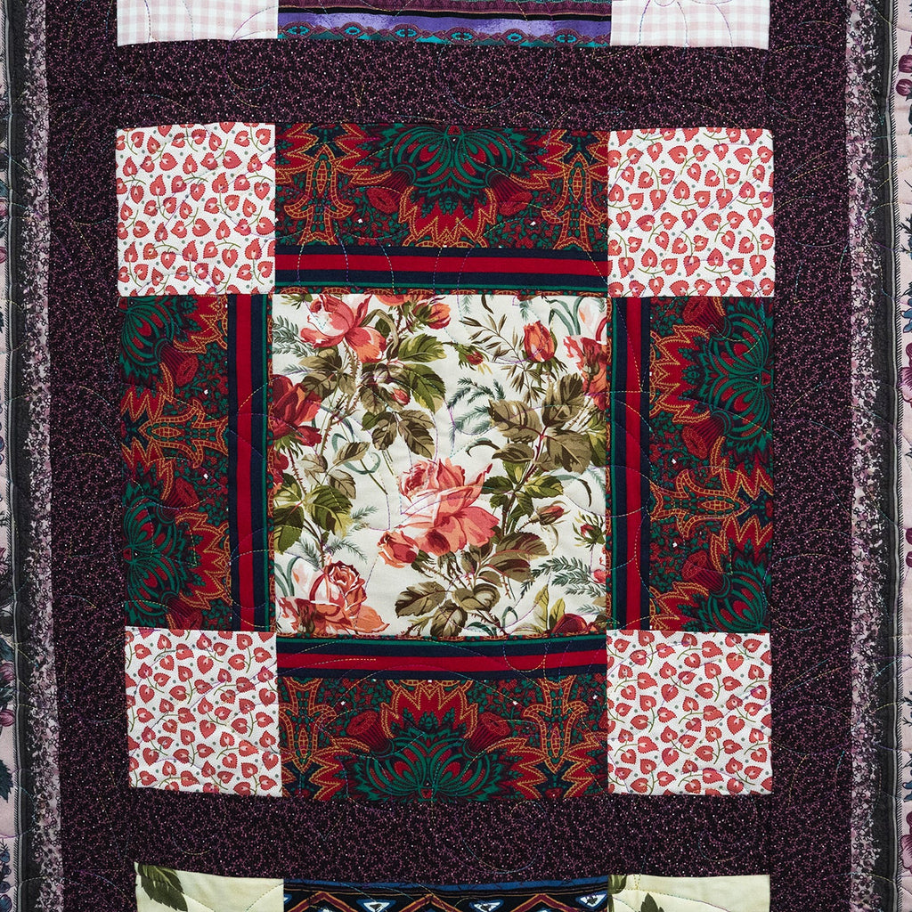 Quilt with floral and geometric patterns on a dark background