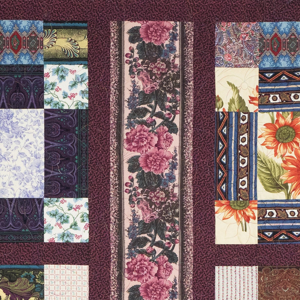 Quilt with various patterns including floral and geometric designs on a dark background.