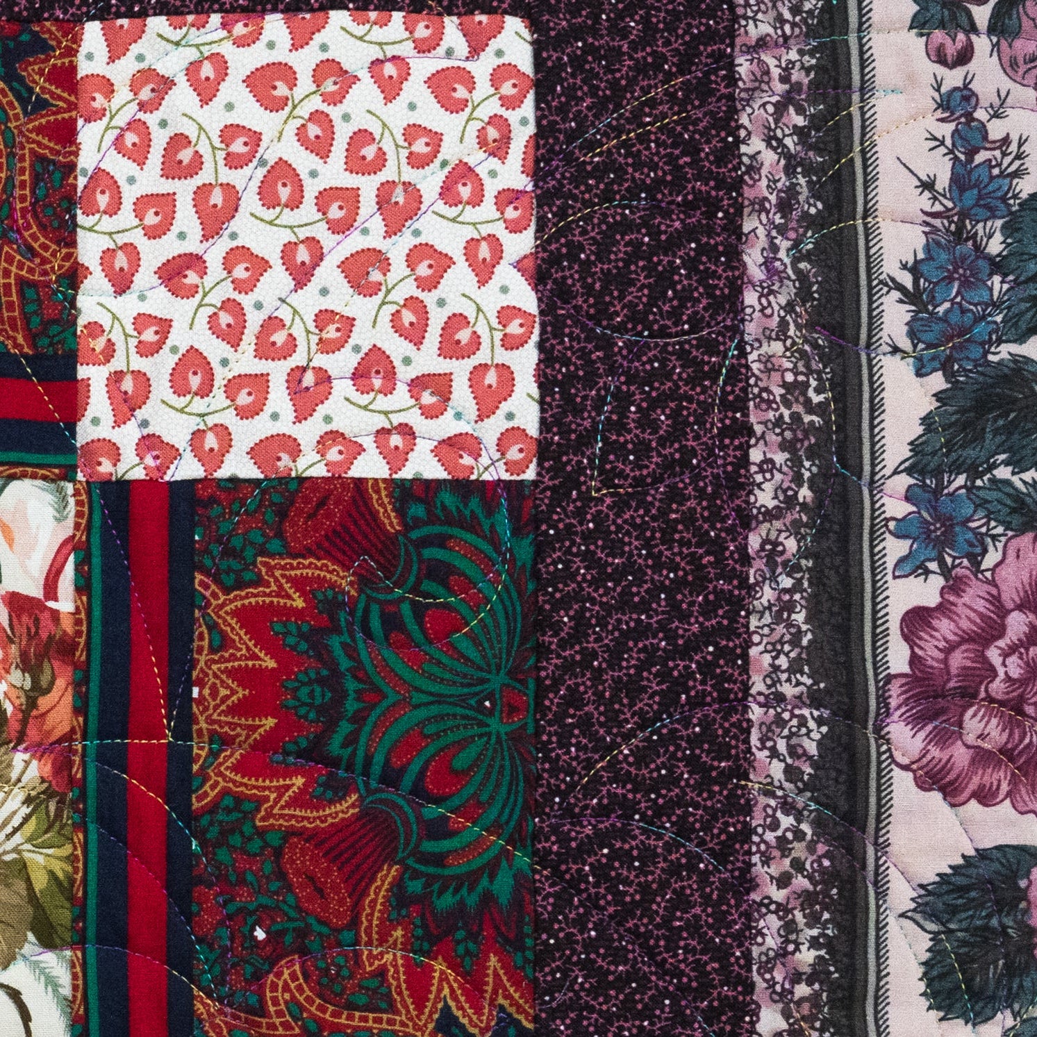 Close-up of a patchwork quilt with various floral and abstract patterns.