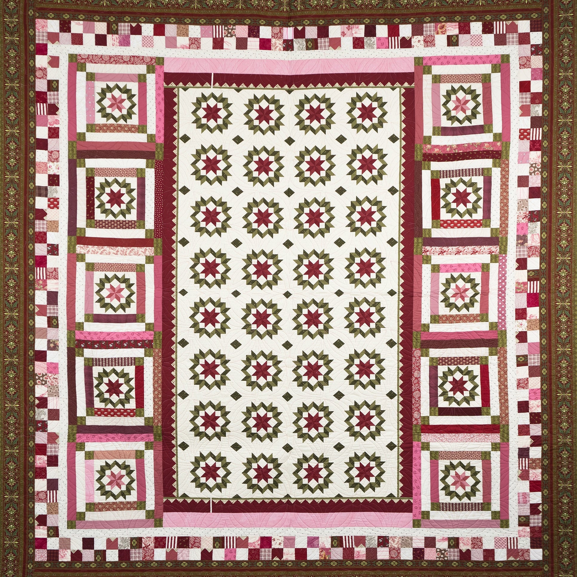 Quilt with a patchwork design featuring pink, green, and white colors on a brown border.