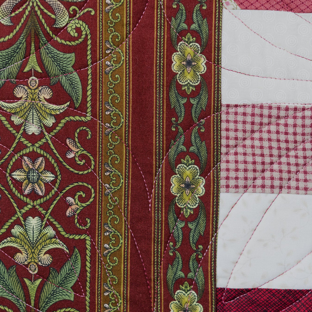 Close-up of a quilt with floral embroidery and patchwork patterns.