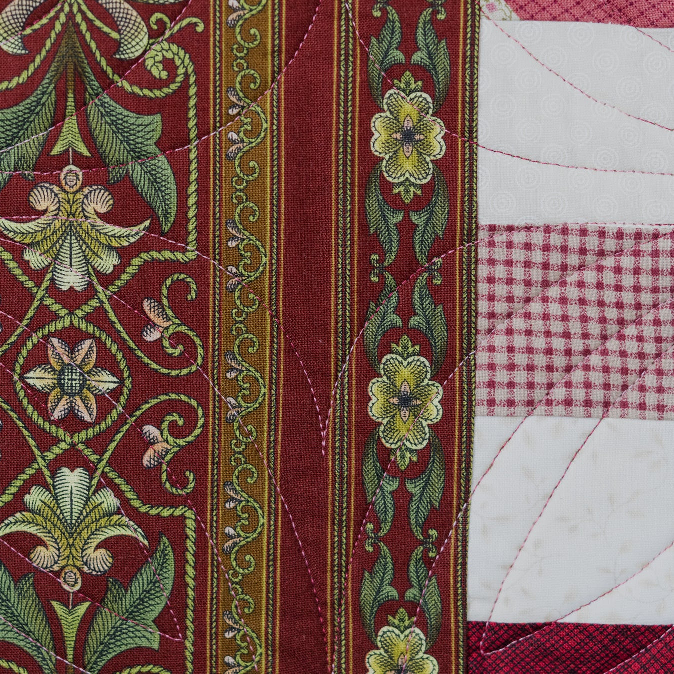 Close-up of a quilt with floral embroidery and patchwork patterns.
