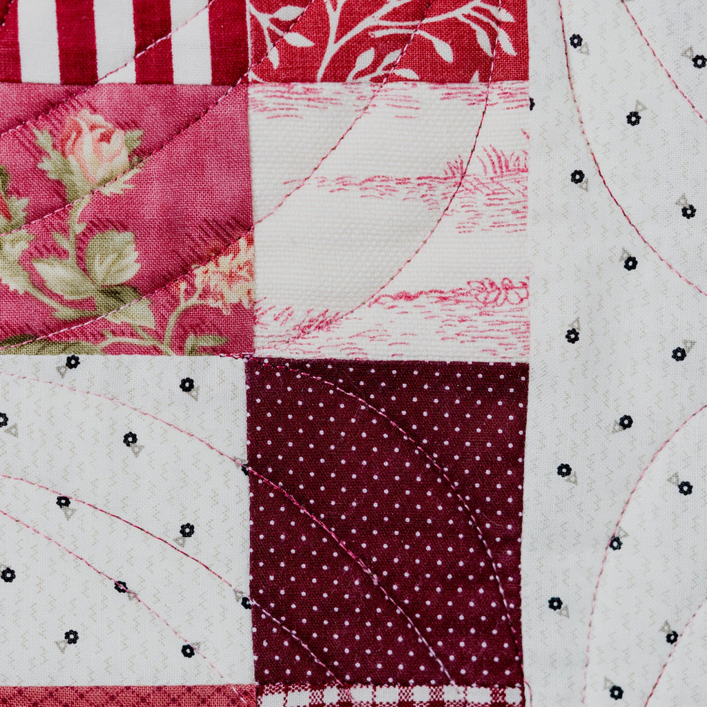 Close-up of a patchwork quilt with floral and geometric patterns.