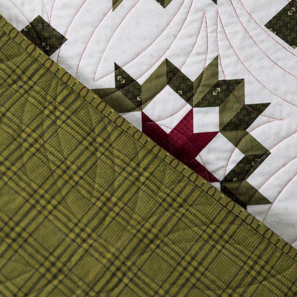 Close-up of a quilt with geometric pattern and green plaid fabric