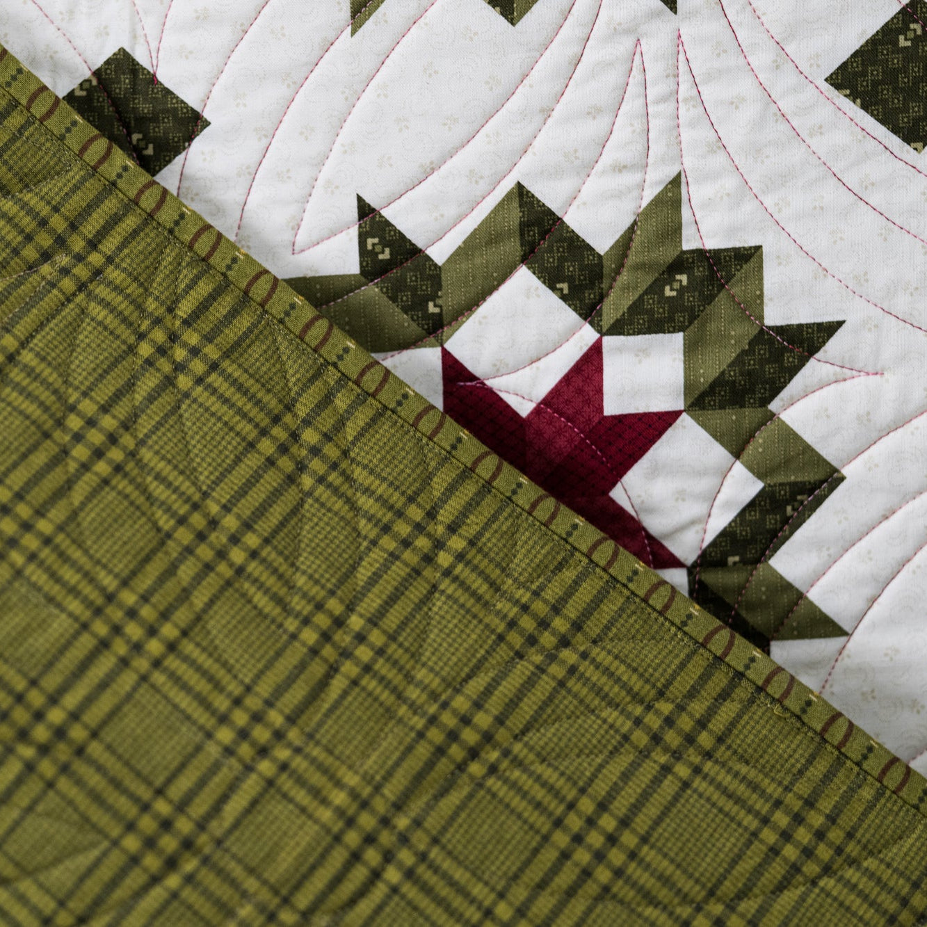 Close-up of a quilt with geometric pattern and green plaid fabric