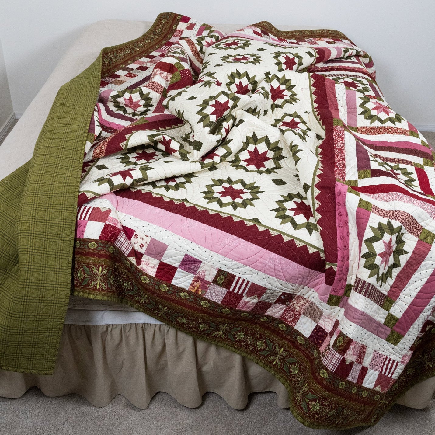 Quilt with a geometric pattern draped over a bed in a room.