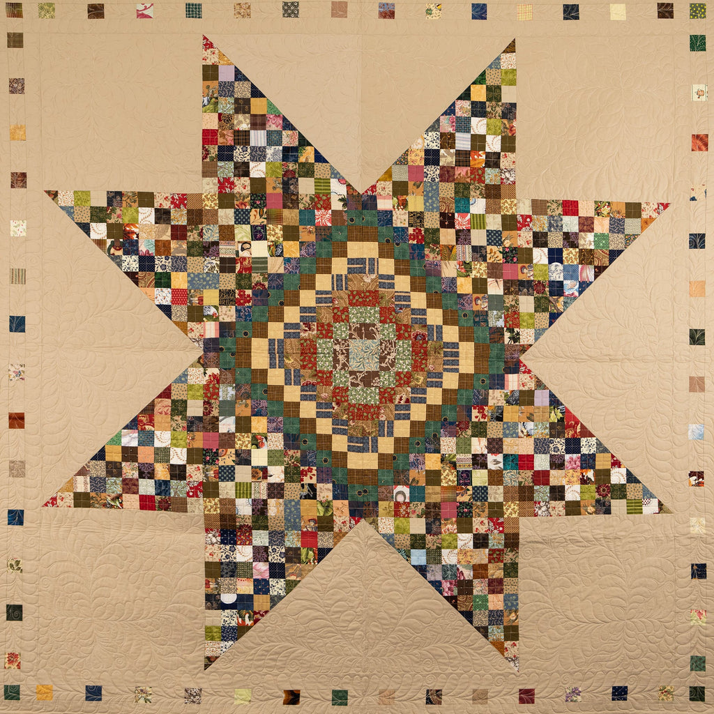 Quilt with a star pattern made of small square patches in various colors on a beige background.