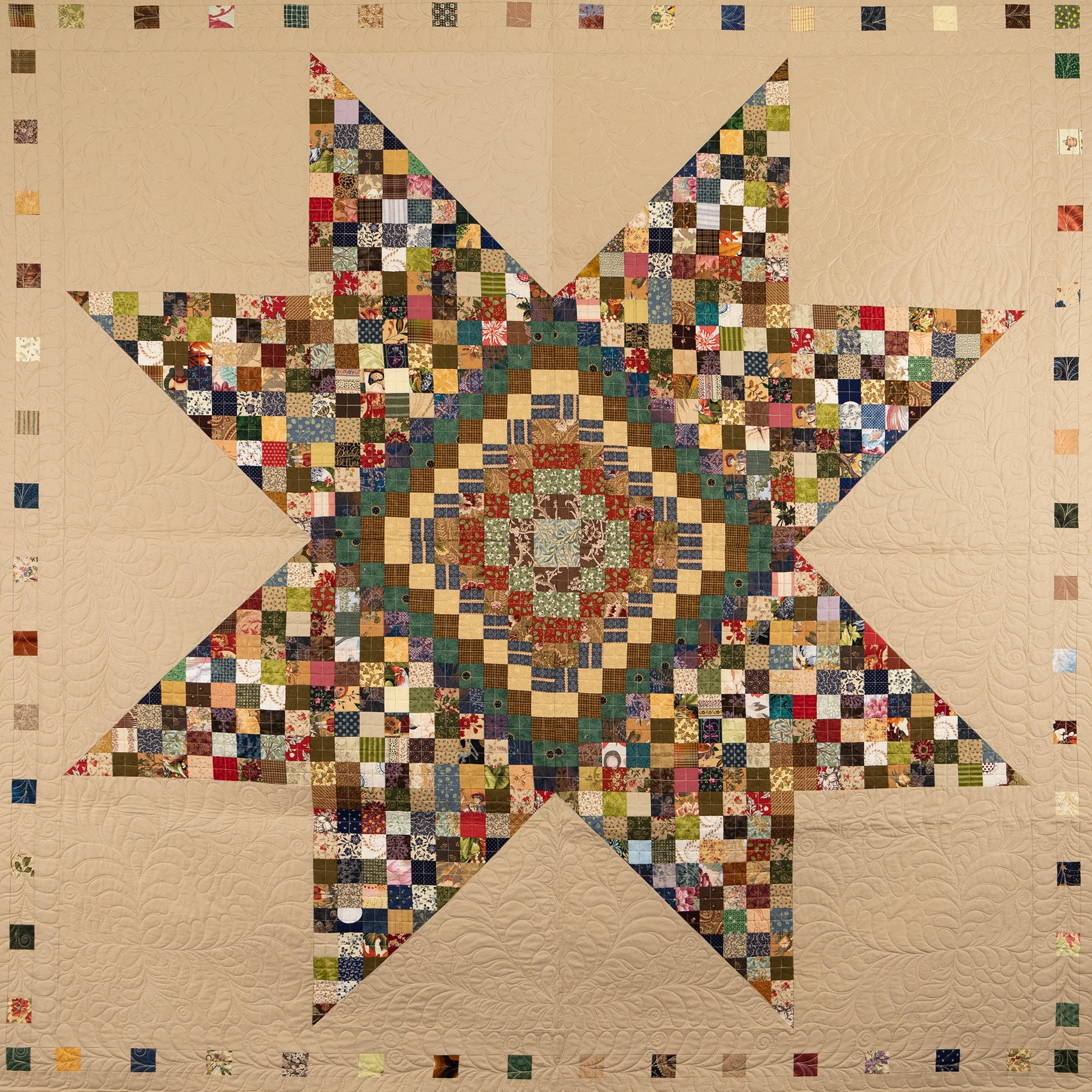 Quilt with a star pattern made of small square patches in various colors on a beige background.